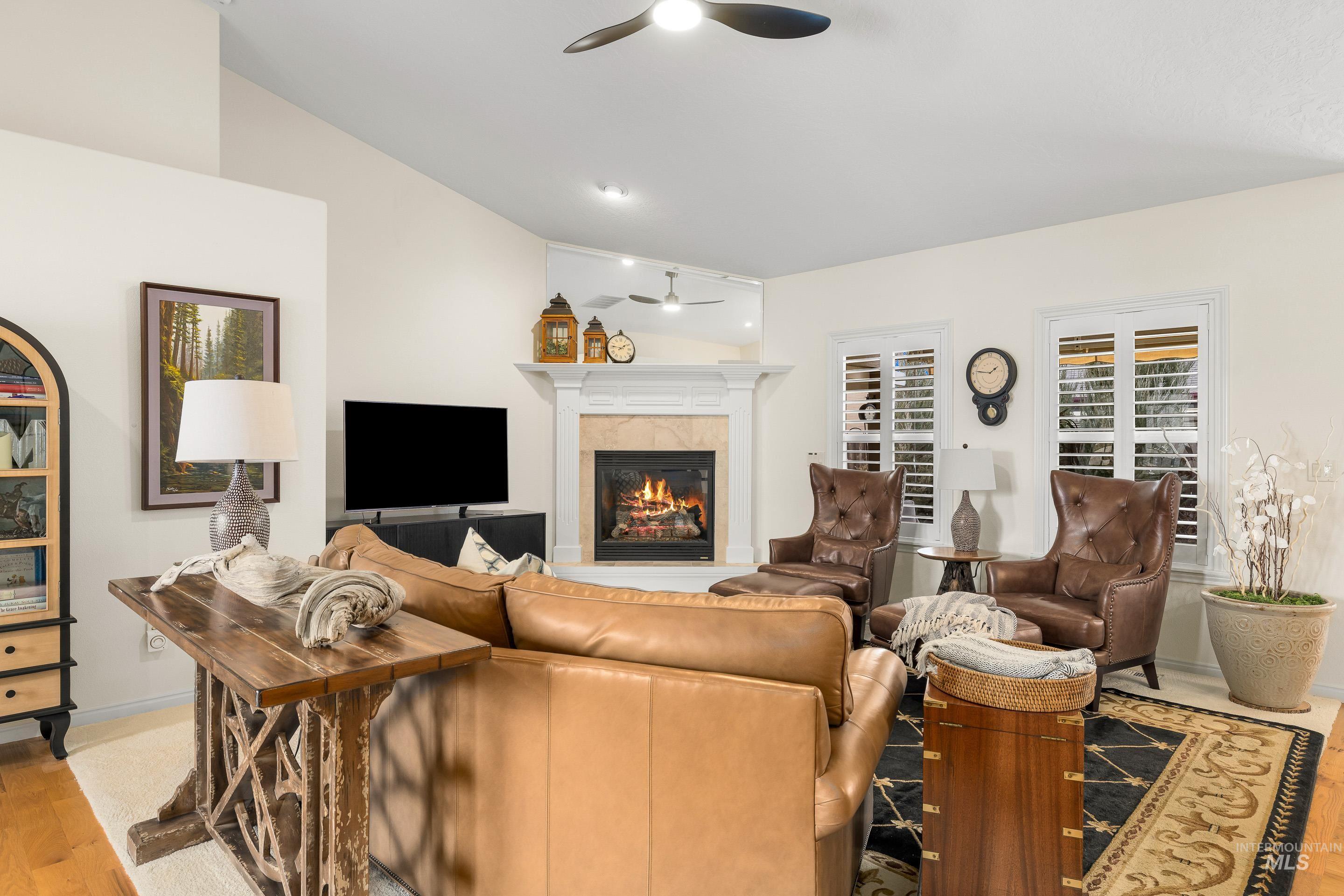 3631 North Alexis Way Meridian, ID 83646 - Photo 7 of 49 Living room featuring a tiled fireplace, lofted ceiling, light wood-style flooring, and a ceiling fan