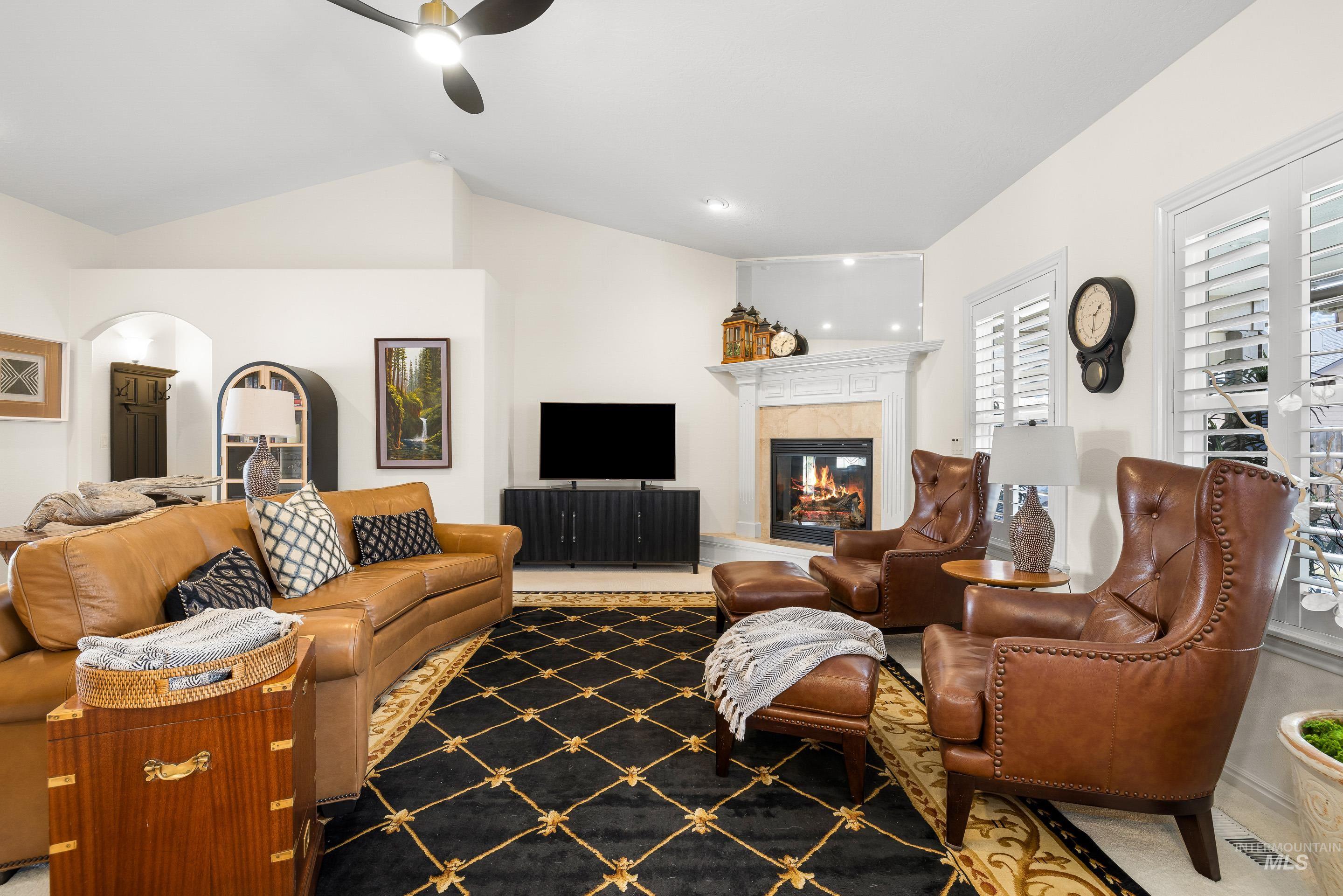 3631 North Alexis Way Meridian, ID 83646 - Photo 8 of 49 Living room with a tiled fireplace, ceiling fan, lofted ceiling, and arched walkways