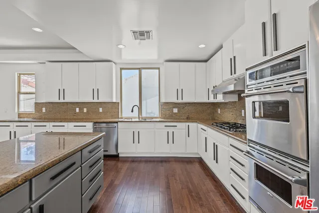 a kitchen with cabinets stainless steel appliances a sink and wooden floor