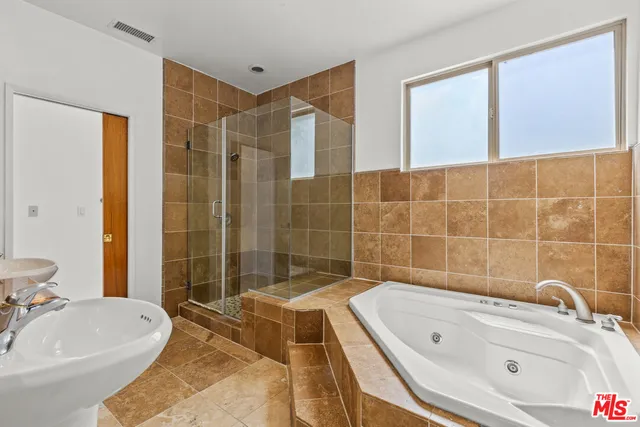 a bathroom with a tub a sink and glass door