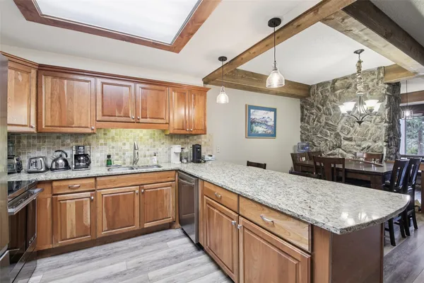 a kitchen with stainless steel appliances granite countertop a sink dishwasher and cabinets with wooden floor