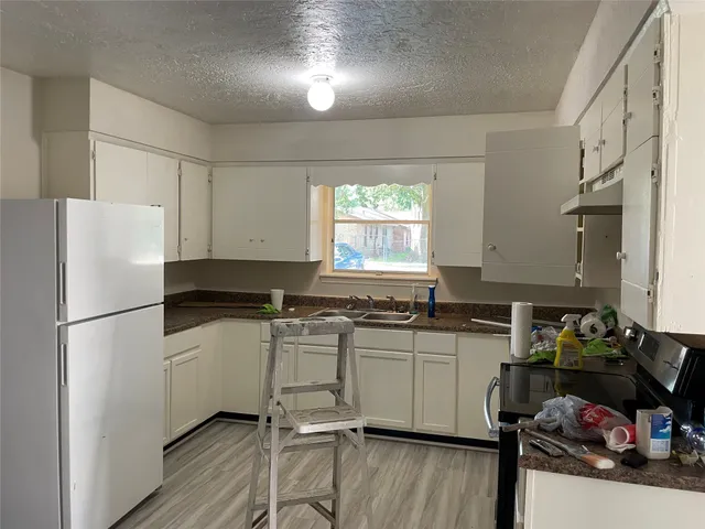 a kitchen with a refrigerator a stove a sink cabinets and wooden floor