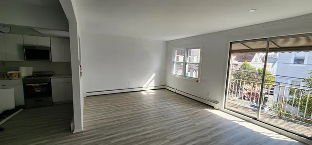 a view of a kitchen with an empty room and wooden floor