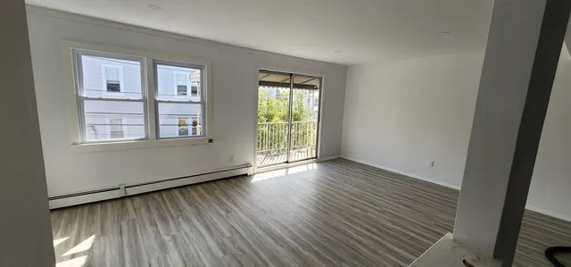 a view of an empty room with wooden floor and a window