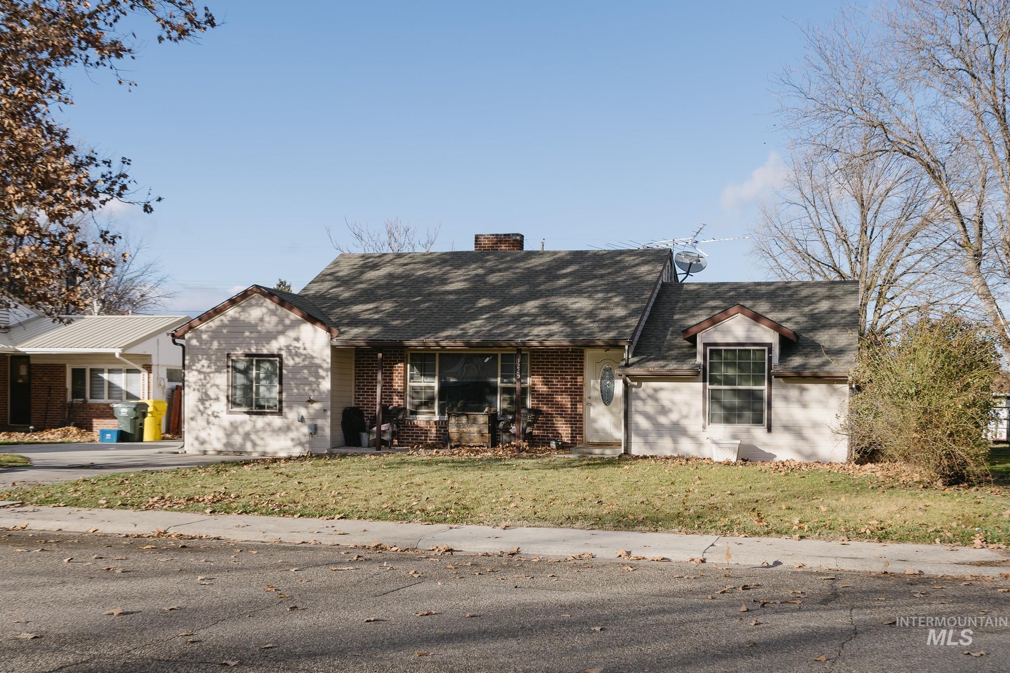 1225 Southwest 3rd Avenue Ontario, OR 97914 - Photo 1 of 1 View of front of home featuring brick siding, a chimney, a front lawn, and a shingled roof