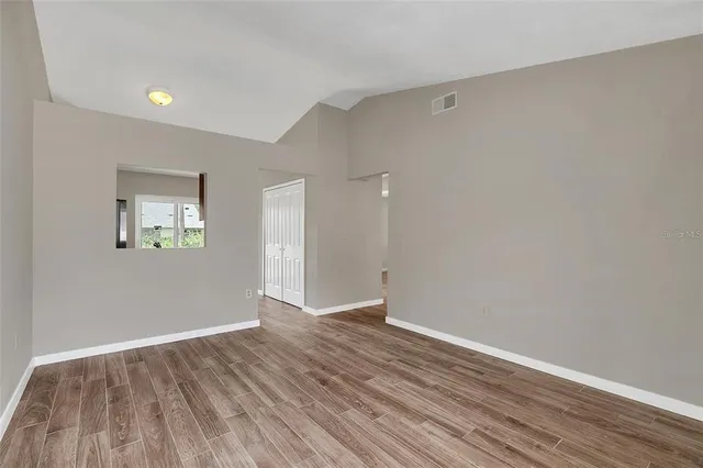 a view of an empty room with wooden floor and a window