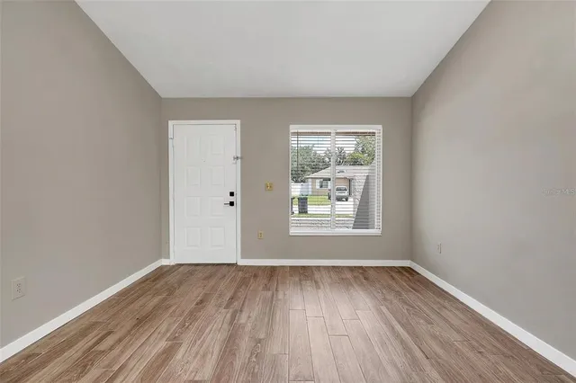 an empty room with wooden floor and windows