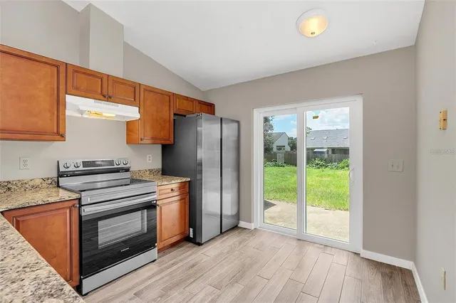 a kitchen with a stove a fridge and wooden floor