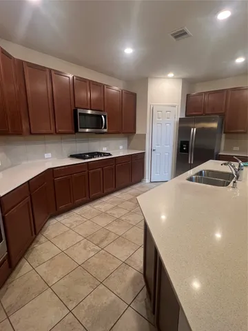 a kitchen with kitchen island granite countertop wooden cabinets a refrigerator and a sink