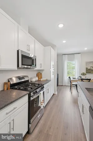 a large kitchen with a stove a sink dishwasher and a microwave oven with wooden floor