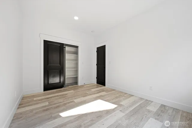 an empty room with wooden floor closet and windows