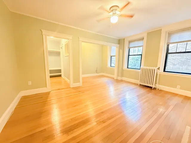 a view of an empty room with window and wooden floor