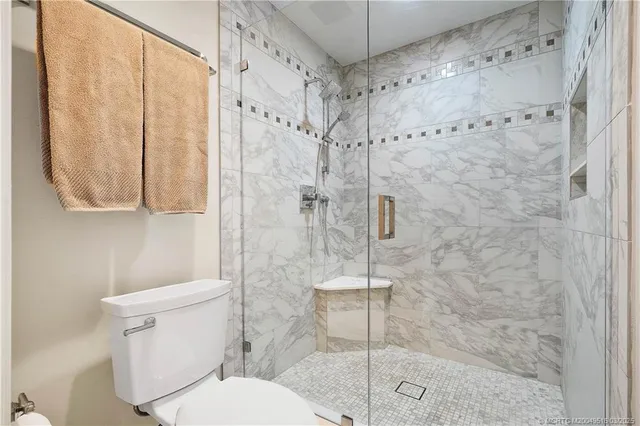 a white toilet sitting next to a shower