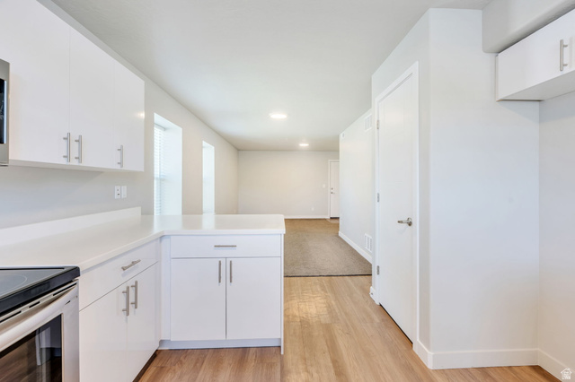 572 South 100 West, Unit E210 Springville, UT 84663 - Photo 16 of 35 Kitchen featuring white cabinetry, light-toned countertops, and wood-finish flooring