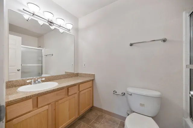 a bathroom with a granite countertop toilet a sink and mirror