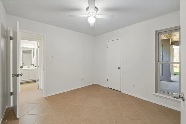 an empty room with a bathroom and a chandelier fan