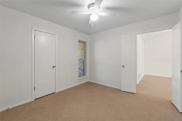 a view of an empty room and chandelier fan