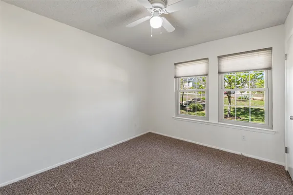 an empty room with a window and a fan