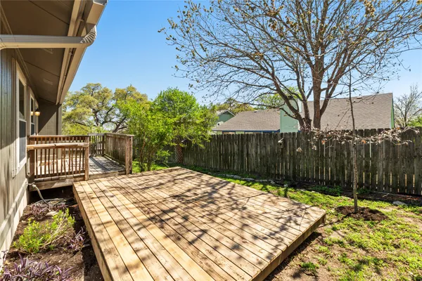 a view of backyard with wooden fence and large trees