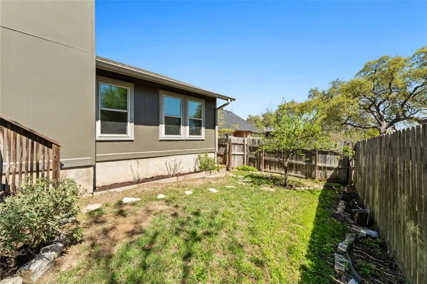 a view of backyard with wooden fence and large trees