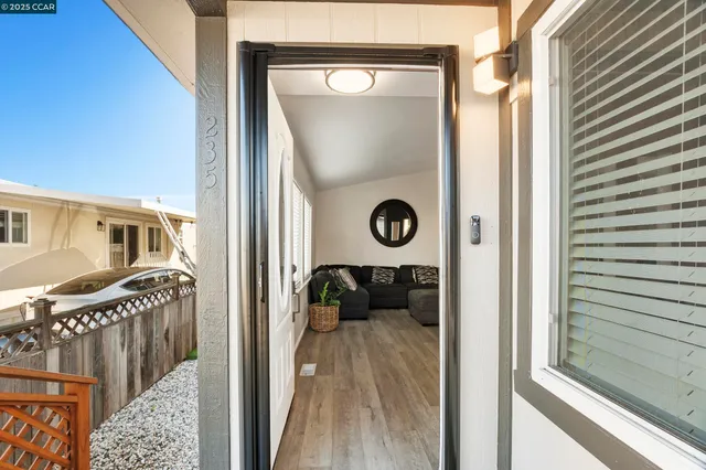 a view of a hallway with wooden floor and living room