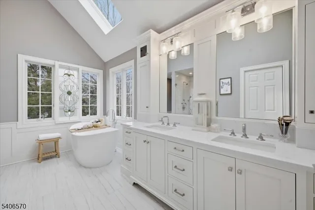 a bathroom with a tub a sink double vanity and mirror