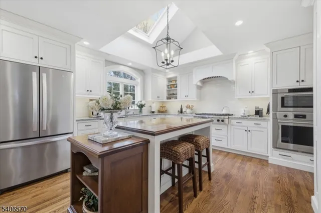 a kitchen with kitchen island granite countertop a sink stainless steel appliances and wooden floor