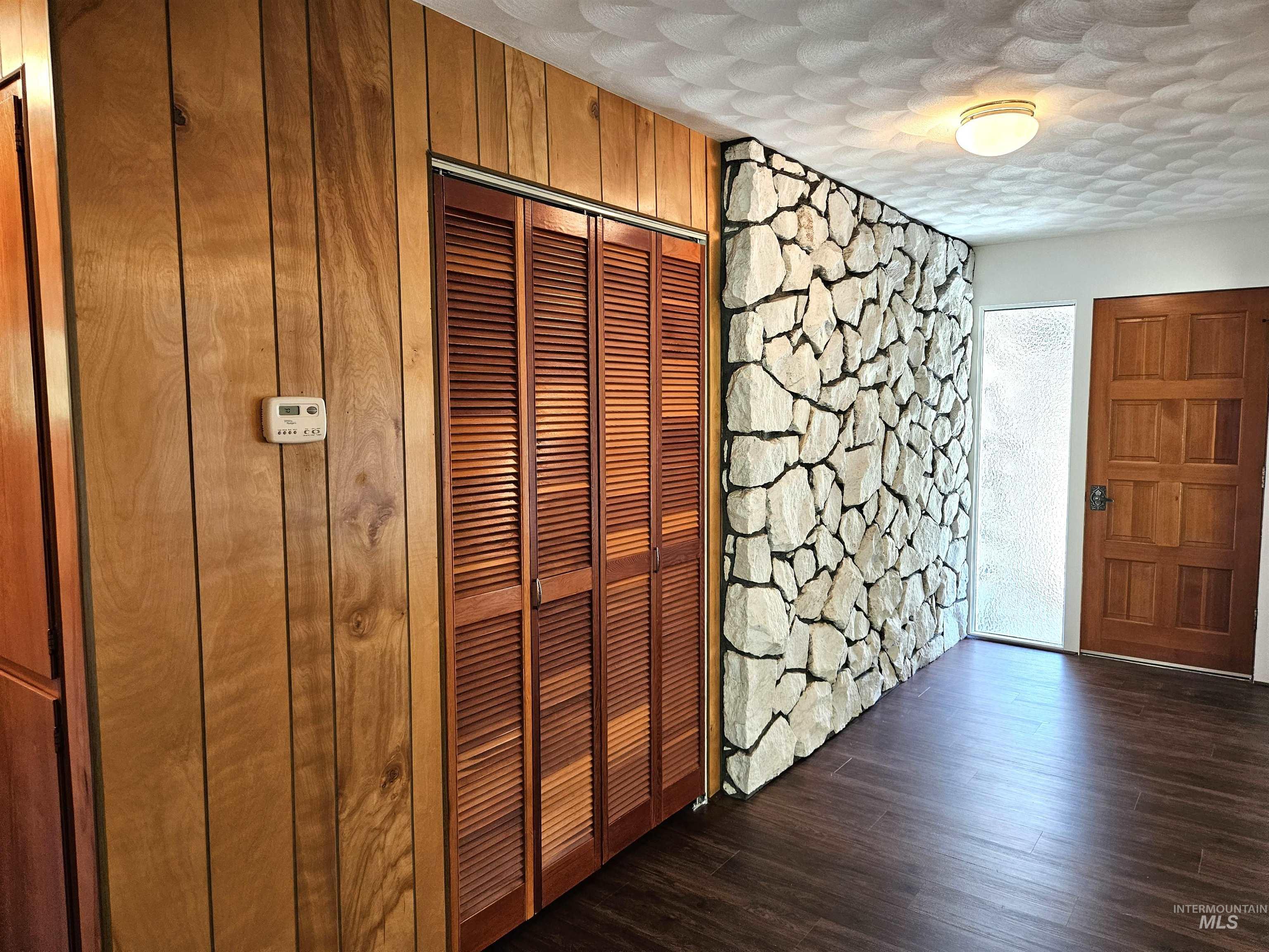 29865 Mission Creek Road Culdesac, ID 83524 - Photo 2 of 43 Entryway featuring a decorative stone accent wall, wood-finish flooring, and a solid wood front door with a textured glass sidelight