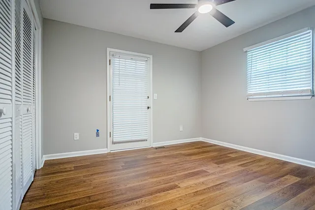 an empty room with wooden floor and windows