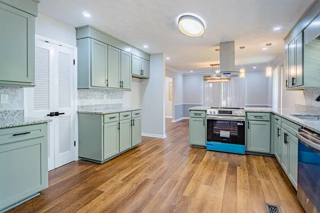 a kitchen with stainless steel appliances kitchen island granite countertop a stove a sink and a refrigerator