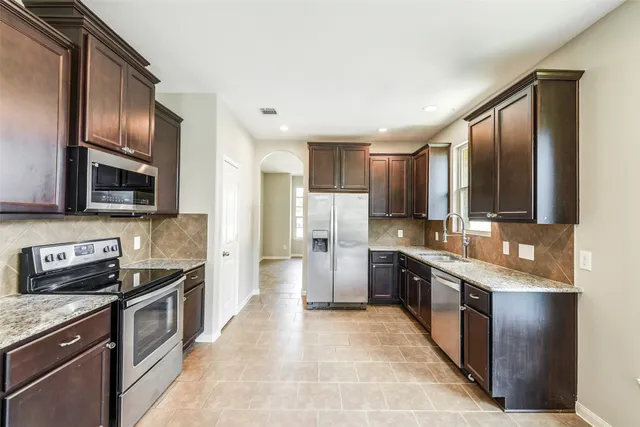 a large kitchen with stainless steel appliances granite countertop a stove top oven a sink and dishwasher