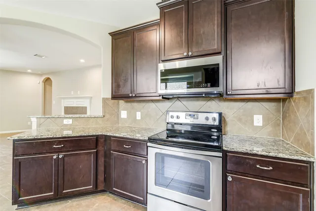 a kitchen with granite countertop a sink stove and microwave