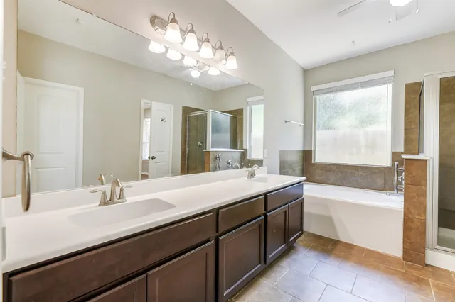 a bathroom with a sink double vanity granite tub and a mirror