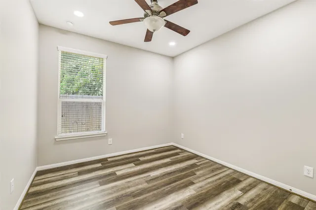 an empty room with a window and ceiling fan