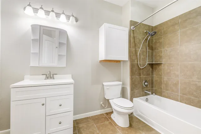 a bathroom with a toilet sink vanity tub and shower