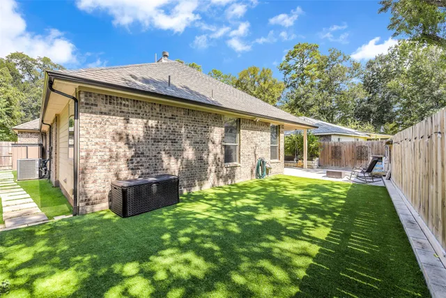 a backyard of a house with table and chairs plants and large tree