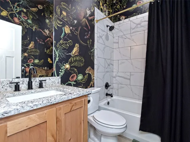 a bathroom with a granite countertop sink and a toilet