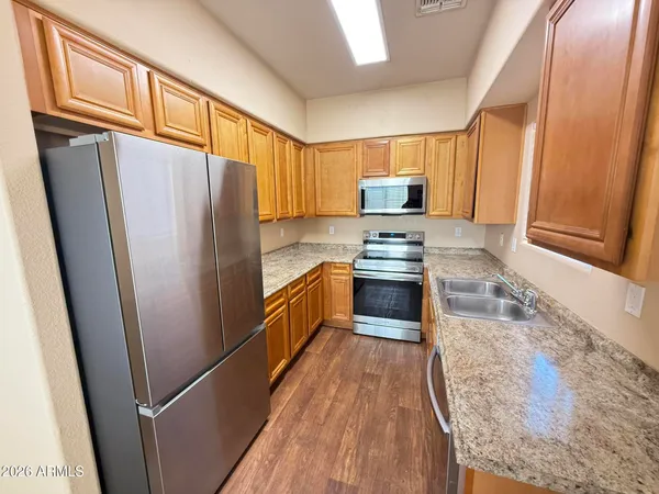 a kitchen with granite countertop a refrigerator a sink dishwasher stove and wooden cabinets
