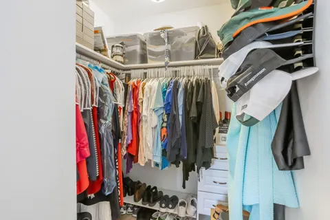 a view of walk in closet with clothes and shoes