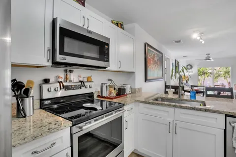 a kitchen with stainless steel appliances granite countertop a sink stove and microwave