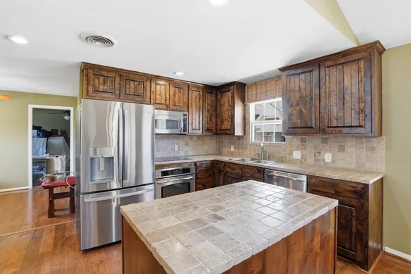 a kitchen with kitchen island a counter top space cabinets stainless steel appliances and a counter space