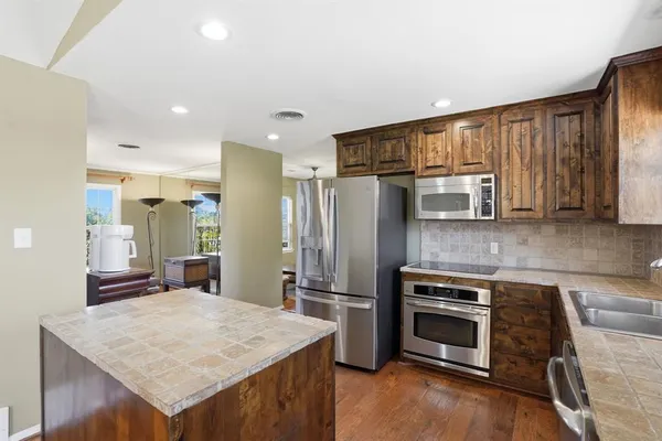 a kitchen with granite countertop wooden cabinets a stove top oven a sink and dishwasher