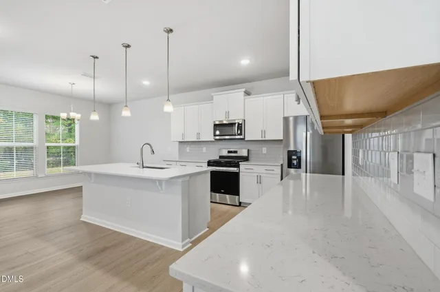 a large white kitchen with lots of counter space a sink appliances and cabinets