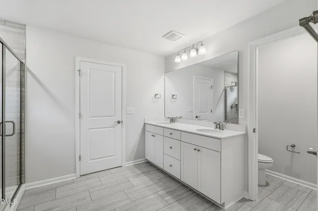 a spacious bathroom with a double vanity sink a large mirror and a shower