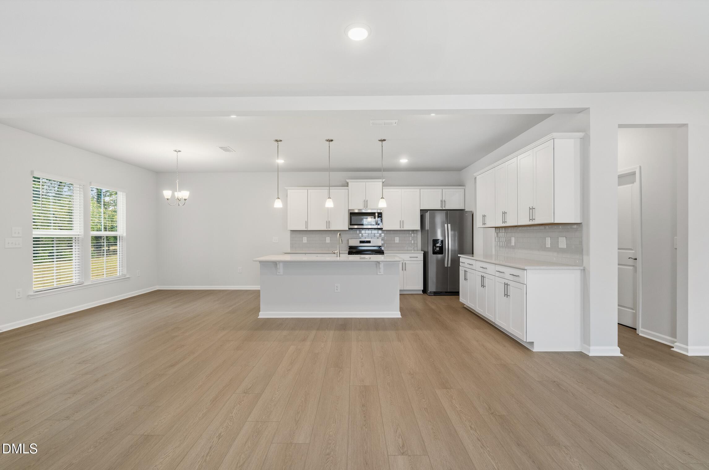 505 Providence Springs Lane Fuquay-Varina, NC 27526 - Photo 8 of 40 a large white kitchen with kitchen island a stove a sink dishwasher and white cabinets with wooden floor