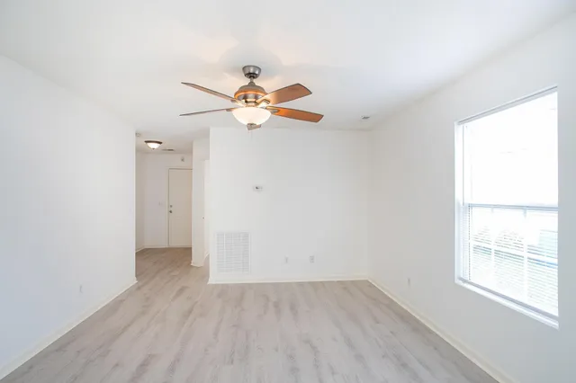 an empty room with a window and a fan