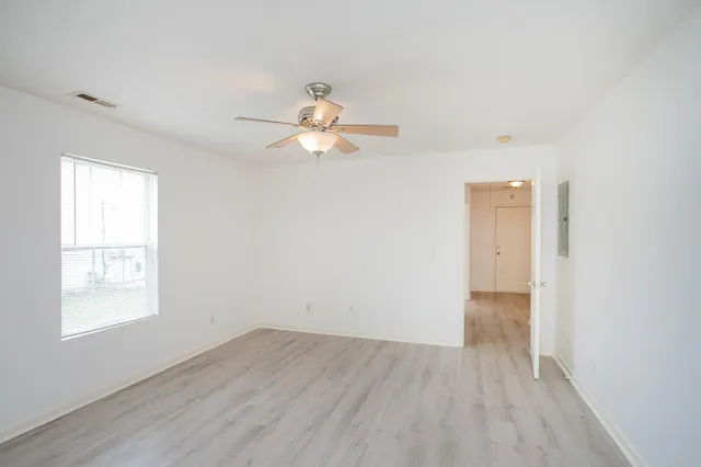 an empty room with wooden floor and windows