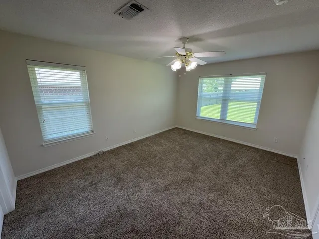 an empty room with windows and fan