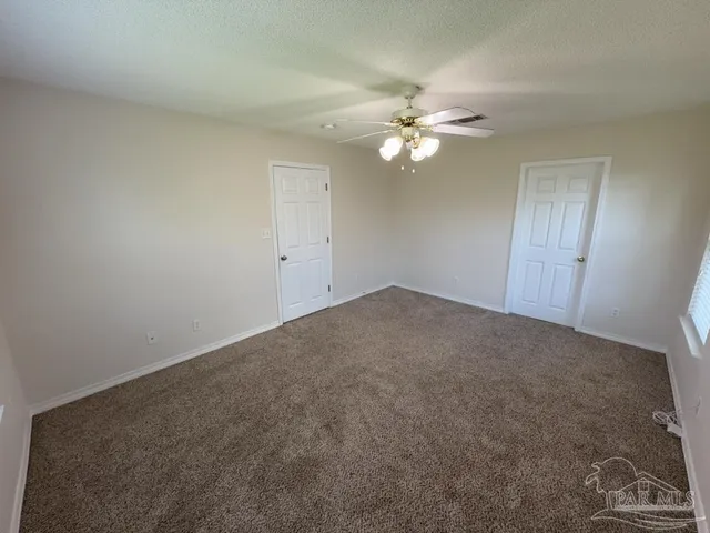 an empty room with a fan and a ceiling fan
