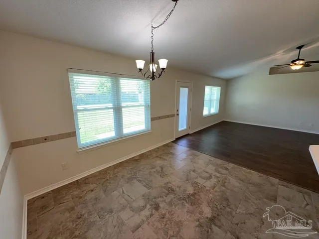 an empty room with wooden floor windows and chandelier
